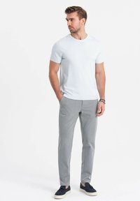 Vaaleansininen lyhythihainen t-paita, harmaat slim-fit-housut ja tummansiniset lenkkarit vaaleilla pohjilla. Asusteessa on yksinkertainen, moderni muotoilu.