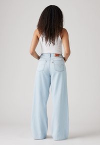 Light blue wide-leg jeans made from denim, featuring a high waist and two back pockets with a branded tag.