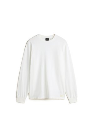 Chemise blanche à manches longues avec col ras du cou, poignets côtelés et petite étiquette logo Vans sur l'ourlet inférieur.