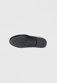 Black shoe sole with a smooth, flat design. Features a textured tread for grip and stitched detailing along the sides.