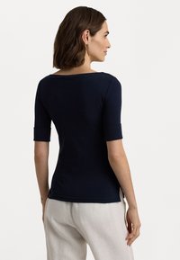 Navy blue fitted t-shirt with a round neckline and short rolled sleeves, made from a smooth cotton blend, featuring side slits.
