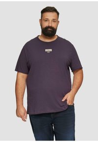 Paarse T-shirt met korte mouwen en een ronde halslijn, voorzien van een klein merklabel op de borst. Gemaakt van lichtgewicht, zachte stof.