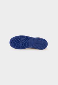 Blauer Gummisneaker-Sohle mit einem kreisförmigen Muster, die strukturierte Grip-Bereiche und einen Logo-Druck im Fußgewölbe aufweist.