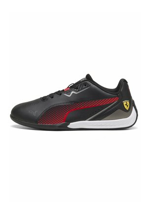 Schwarzer und roter Puma-Sneaker mit Ferrari-Logo an der Ferse, schwarzen Schnürsenkeln und weißer Sohle, von der Seite auf weißem Hintergrund gezeigt.