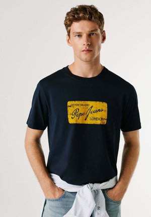 Marineblå bomuldst-shirt med en gul rektangulær grafik med teksten "DENIM BRAND" og "Pepe Jeans LONDON" i sort. Casual pasform.