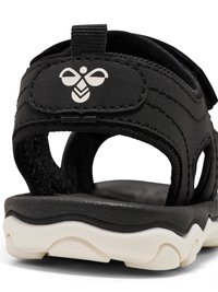 Sort sandal med åben hæl, hvid sål og justerbar rem med hvidt bi-logo på hælen.
