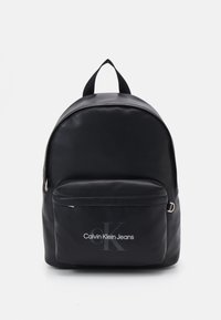 Zaino nero realizzato in materiale morbido, con una tasca anteriore con zip e un logo. Include spallacci in tessuto doppi e una parte superiore arrotondata.