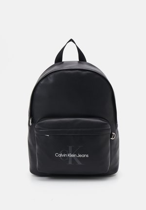 Zaino nero realizzato in materiale morbido, con una tasca anteriore con zip e un logo. Include spallacci in tessuto doppi e una parte superiore arrotondata.
