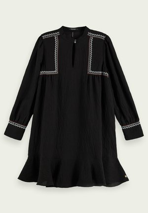 Svart långärmad klänning med rund halsringning, nyckelhålsutskärning, broderade detaljer på axlarna och volangade fållar. Texturerad tyg.