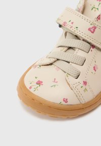 Μπεζ δερμάτινο παπούτσι με ανθικό μοτίβο σε ροζ και πράσινο. Διαθέτει λουράκι με βέλκρο και ανάγλυφη καουτσούκ σόλα.