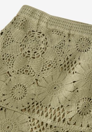 Tissu au crochet dans une couleur verte atténuée, avec des motifs floraux et des motifs ajourés. Le design a un aspect texturé et superposé avec des détails complexes.