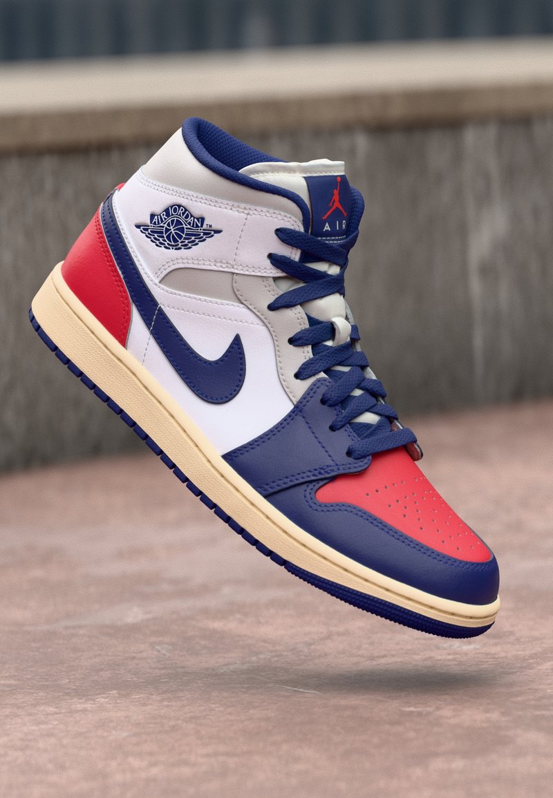 Sneaker alta con pannelli in pelle bianca, rossa e blu, punta perforata, suola spessa di colore crema e lacci blu con logo di lato.