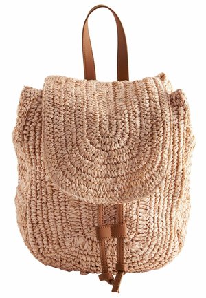 Petit sac à dos beige tissé avec rabat arrondi et fermeture par sangle en cuir marron et poignée.