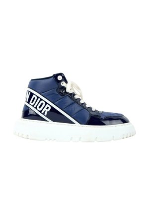 Marineblauwe hoge sneaker met witte zool en veters, met witte "Dior" branding op de hielriem.