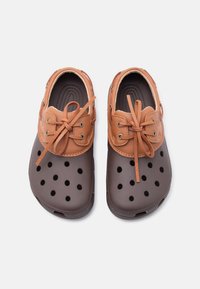 Ζευγάρι καφέ και ταμπά καθημερινών παπουτσιών με διάτρητη περιοχή στη μύτη και δερμάτινα κορδόνια, απεικονισμένα από πάνω σε λευκό φόντο.