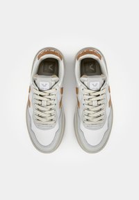 Sneakers with a white mesh and leather upper, light grey outsole, and brown accents. Features round laces and a logo on the tongue.