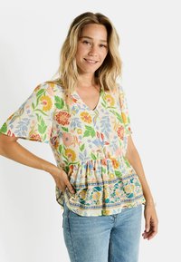 Blusa de jersey con estampado floral en color crema, con escote en V y mangas cortas, que presenta una cintura fruncida y un detalle de banda colorida en el dobladillo. Tela ligera.
