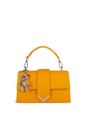 Borsa a mano in pelle gialla con manico superiore e chiusura a patta, con portachiavi a forma di orso gioiellato e colorato attaccato a un lato.