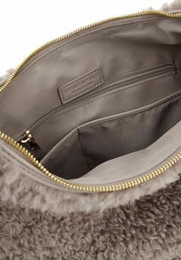 Borsa interna in tessuto grigio con cerniera dorata. Include una tasca con cerniera e un'etichetta in tessuto. La morbida texture esterna è visibile.