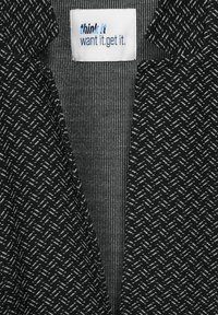 Kariéra černobílé tkaniny se vzorem vafle. Obsahuje štítek s textem "mysli to, chtěj to, získej to" a texturovaný pruhovaný vzor.