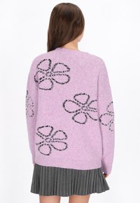 Liliowy sweter z dzianiny z czarnym wzorem kwiatowym, o luźnym kroju i długich rękawach. Zawiera ściągacz w dekolcie i na dole.