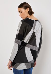 Langsleeve top met een zwart, grijs en lichtgrijs abstract patroon. Gemaakt van zachte stof, met een ronde halslijn en een relaxte pasvorm.