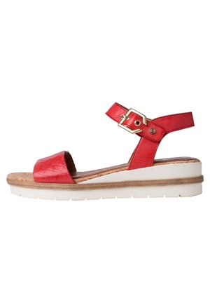 Sandale rouge à bout ouvert avec bride à la cheville et boucle dorée, semelle intérieure en liège rembourrée, et semelle plateforme blanche avec couche intermédiaire beige.