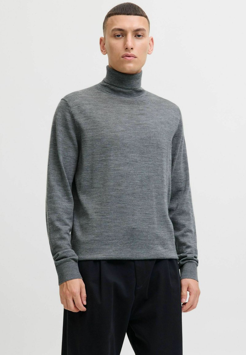 Sivi turtleneck pulover napravljen od mekog materijala, s dugim rukavima i rebrastim manžetama, uparen sa tamnim širokim hlačama.