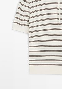 Bílé pletené tričko s krátkým rukávem s tenkými černými vodorovnými pruhy a knoflíkovou légou na horní straně.