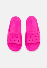 Sandales à glissière fuchsia en caoutchouc avec une texture lisse, dotées de trous de ventilation et d'un logo de marque en relief sur la semelle intérieure.