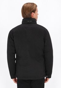 Sort vinterjakke med høj krave, glat tekstur og polstret design. Har minimalistiske sømme og en trykknapdetalje ved nederste kant.