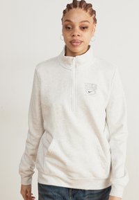 Lys grå quarter-zip fleece med høy krage, med Nike-logo og frontlommer, laget av mykt, strukturert materiale.