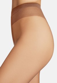 Collant beige trasparenti con una texture liscia, una cintura larga marrone e un bordo senza cuciture, progettati per il comfort e un aspetto naturale.