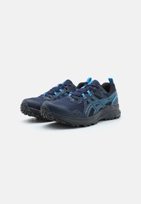 Baskets de sport bleu marine avec accents noirs, dotées d'une tige en maille, de lacets bleus et d'une semelle extérieure en caoutchouc texturé pour une meilleure traction.
