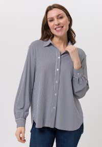 Gestreifte Bluse aus marineblauem und weißem Baumwollstoff, mit durchgehender Knopfleiste, langen Ärmeln mit Manschetten und einem lockeren Schnitt mit Seitenschlitzen.