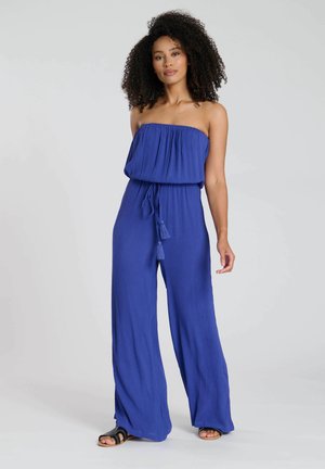 Jumpsuit blu senza spalline realizzato in tessuto leggero, caratterizzato da una vestibilità ampia, un elastico in vita e dettagli con frange al nodo.