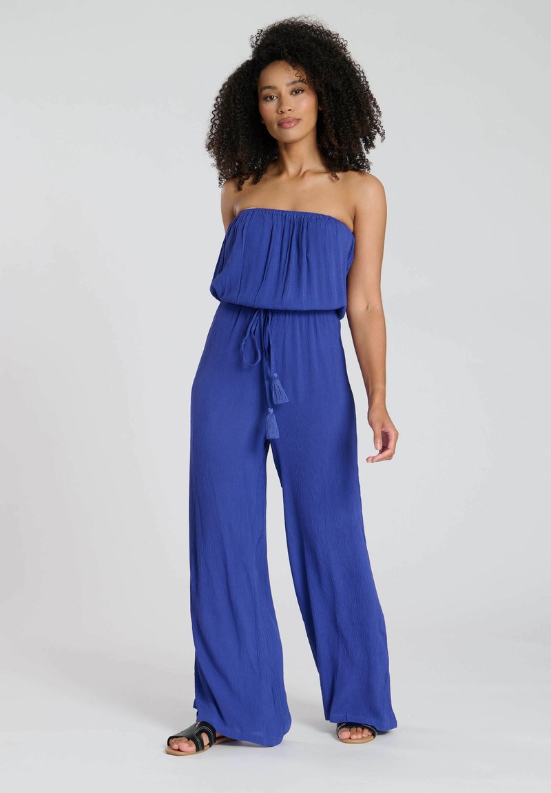 Mono azul sin mangas hecho de tejido ligero, con un corte holgado, cinturilla elástica y detalle de borlas en el lazo.