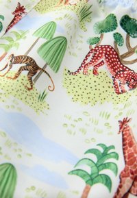 Bavlnená tkanina s témou safari, na ktorej sú ilustrované zvieratá vrátane žirafy, tigra a patterned geparda, medzi zelenými stromami a kríkmi.