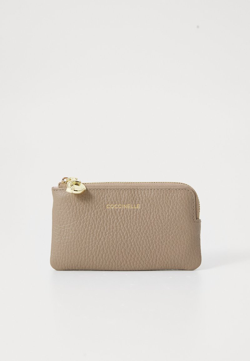 Tan leather zip wallet with textured surface, gold hardware, and embossed logo on the front. Compact rectangular shape.