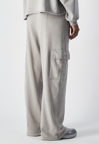 Lichtgrijze, zachte cargobroek met een losse pasvorm. Heeft een zijzak en ribgebreide boorden bij de enkels. Ontworpen voor comfort.