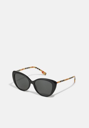 Occhiali da sole cat-eye neri con lenti scure. Le astine presentano un motivo a strisce multicolori su uno sfondo chiaro. Montatura in plastica liscia.