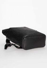 Zaino in pelle nera con forma rettangolare, spallacci regolabili, texture liscia e un logo discreto, progettato per versatilità e durata.