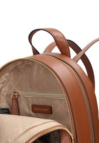 Zaino in pelle marrone con cerniera color oro, con fodera interna beige e una piccola tasca con cerniera etichettata "MICHAEL KORS".