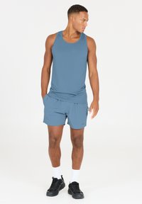 Herre sportstanktop og shorts i en dæmpet blå farve; lavet af letvægtsmateriale, med en afslappet pasform og sidelommer.