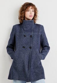 Navy blue wool coat with a high collar, double-breasted design, two front pockets, and black buttons, featuring a textured finish.