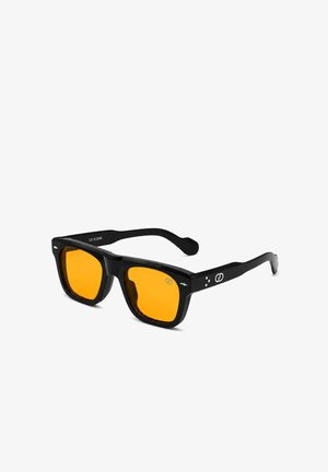 Schwarze rechteckige Sonnenbrille mit dicken Rahmen und leuchtend orangefarbenen Gläsern, mit kleinen weißen Logos an den Bügeln und nahe den Schläfen.
