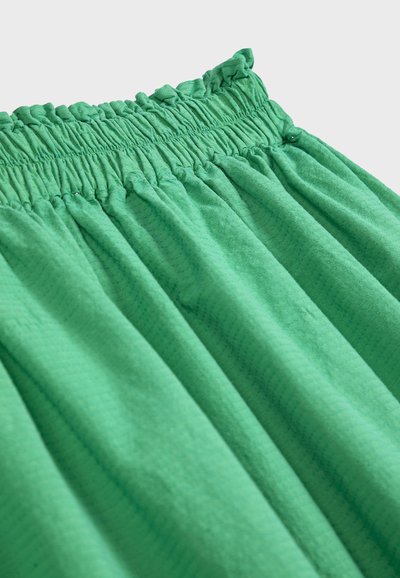 Zielona spódnica z tkaniny z elastycznym, marszczonym paskiem i subtelnym teksturowanym wzorem, pokazana z bliska na jednolitym tle.