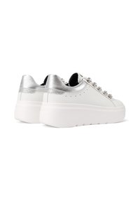 Sneakers bianchi con piattaforma, con accenti metallici argento sul tallone e borchie decorative argento che sostituiscono i tradizionali lacci, vista laterale su sfondo bianco.