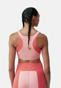 Athletic bra in gradient shades of pink, featuring a racerback design and smooth texture. Includes subtle branding on the band.