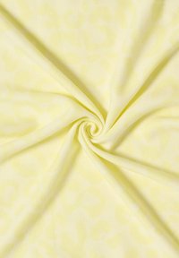 Tissu jaune présentant un motif discret de léopard, texture légère et finition lisse, disposé en forme de spirale.